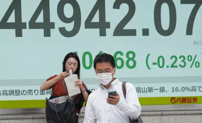 People stand in front of an electronic stock board showing Japan's Nikkei 225 index at a securities firm Tuesday, Sept. 30, 2025, in Tokyo. (AP Photo/Eugene Hoshiko)