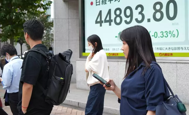 People stand in front of an electronic stock board showing Japan's Nikkei 225 index at a securities firm Tuesday, Sept. 30, 2025, in Tokyo. (AP Photo/Eugene Hoshiko)