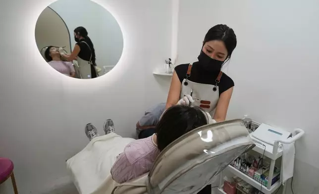 Kim Sho-yun, 45, who runs a cosmetic tattoo studio, draws a woman's eyebrow with pencil as she consults for semi-permanent cosmetic tattoos in Hanam, South Korea, Thursday, Sept. 18, 2025. (AP Photo/Lee Jin-man)