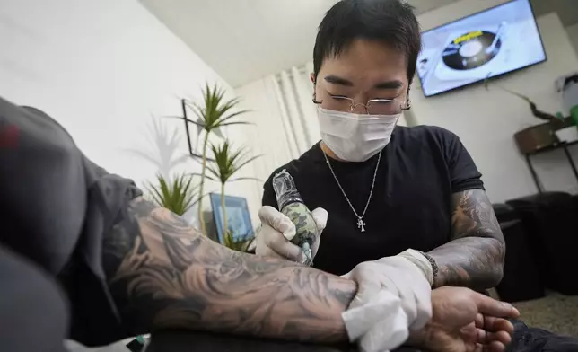 Tattoo artist Song Jaemin works to tattoo an image of Jesus Christ on the forearm of Lee Byong-joo at his studio in Goyang, South Korea, Thursday, Sept. 18, 2025. (AP Photo/Ahn Young-joon)