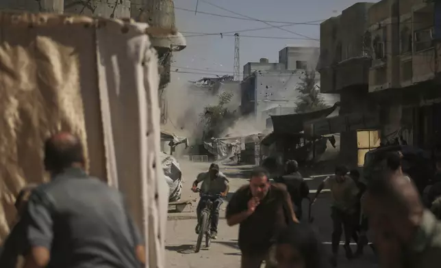 Palestinians run for cover during an Israeli military strike on a building in Gaza City, Saturday, Sept. 13, 2025. (AP Photo/Yousef Al Zanoun)