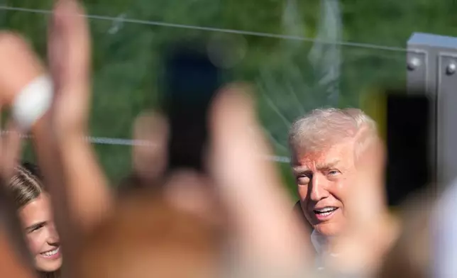 President Donald Trump greets the crowd accompanied by his granddaughter Kai Trump, left, as he arrives at the Ryder Cup golf tournament on the Bethpage Black golf course in Farmingdale, N.Y., Friday, Sept. 26, 2025. (AP Photo/Alex Brandon)
