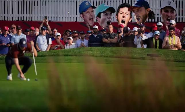 Fans hold up photos as Europe's Matthew Fitzpatrick lines up a putt on the seventh hole at Bethpage Black golf course during the Ryder Cup golf tournament, Saturday, Sept. 27, 2025, in Farmingdale, N.Y. (AP Photo/Matt Slocum)