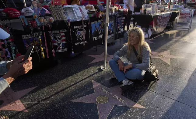 FILE - Silvia Camino, visiting from Argentina, takes photos with the Donald Trump star on the Hollywood Walk of Fame in Los Angeles, Friday, April 4, 2025. (AP Photo/Jae C. Hong, File)