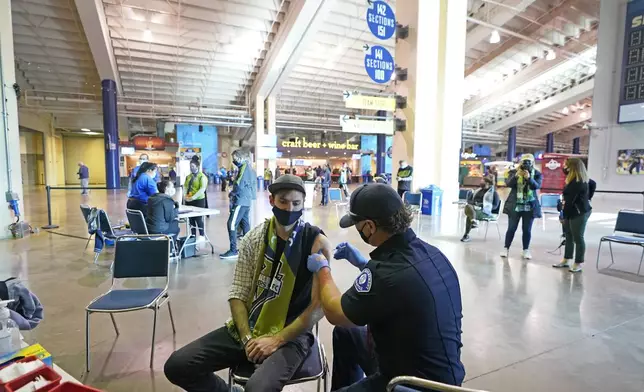 FILE - In this May 2, 2021, file photo, Austin Kennedy, left, a Seattle Sounders season ticket holder, gets the Johnson &amp; Johnson COVID-19 vaccine at a clinic in a concourse at Lumen Field in Seattle, prior to an MLS soccer match between the Sounders and the Los Angeles Galaxy. (AP Photo/Ted S. Warren, File)