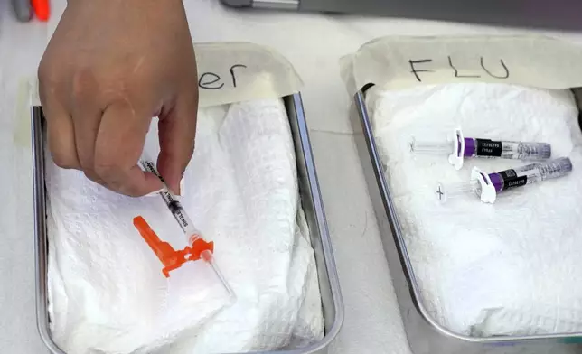 FILE - A COVID vaccine, left, is readied as a flu vaccine sits nearby at the L.A. Care and Blue Shield of California Promise Health Plans' Community Resource Center where they were offering members and the public free flu and COVID-19 vaccines, Oct. 28, 2022, in Lynwood, Calif. (AP Photo/Mark J. Terrill, file)