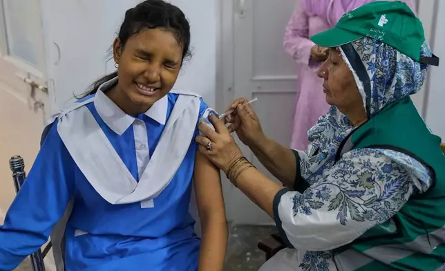 A health worker gives an injection of human papillomavirus (HPV) vaccine to a girl during a campaign aiming to protect girls from cervical cancer, at a school in Lahore, Pakistan, Monday, Sept. 22, 2025. (AP Photo/K.M. Chaudary)