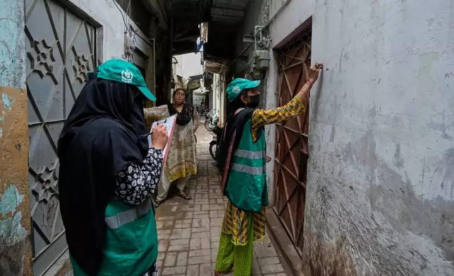 A heath worker marks on the wall of a home during a human papillomavirus (HPV) vaccination campaign aiming to protect girls from cervical cancer, at a neighbourhood of Karachi, Pakistan, Wednesday, Sept. 24, 2025. (AP Photo/Fareed Khan)