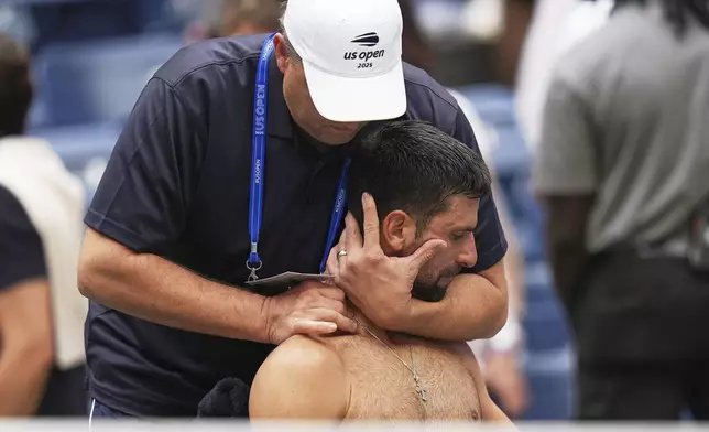 Novak Djokovic, of Serbia, has his back stretched during the men's singles semifinals of the U.S. Open tennis championships, Friday, Sept. 5, 2025, in New York. (AP Photo/Seth Wenig)