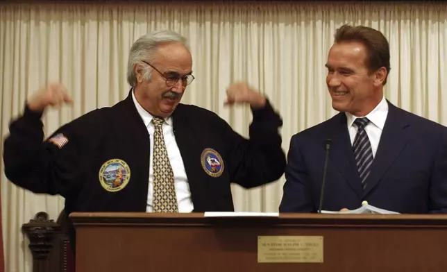 FILE - State Sen. President Pro Tem John Burton, D-San Francisco, left, flexes his muscles for Gov. Arnold Schwarzenegger, after Schwarzenegger gave Burton a jacket as a going away gift during the last day of the Legislative session held at the Capitol in Sacramento, Calif., Friday, Aug. 27, 2004. (AP Photo/Rich Pedroncelli,File)