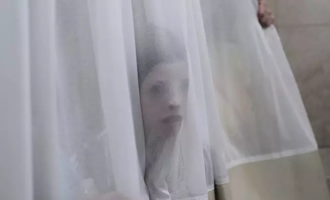 A mourner looks trough a curtain during the funeral of Levi Yitzhak Pash, who was killed along with five other Israelis in a shooting attack by two Palestinian gunmen at a bus stop in Jerusalem Monday, Sept. 8, 2025. (AP Photo/Ariel Schalit)