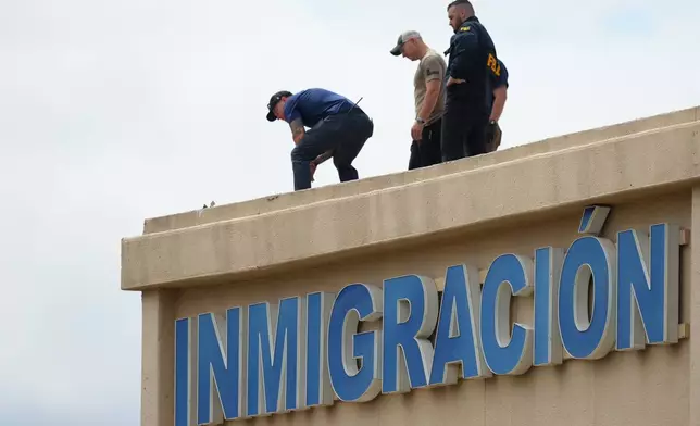 Law enforcement agents look around the roof of a building near the scene of a shooting at a U.S. Immigration and Customs Enforcement office in Dallas on Wednesday, Sept. 24, 2025. (AP Photo/Julio Cortez)