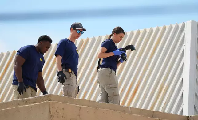 Law enforcement agents investigate the roof of an apartment building near the scene of a shooting at a U.S. Immigration and Customs Enforcement office in Dallas on Wednesday, Sept. 24, 2025. (AP Photo/Julio Cortez)