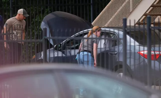 Law enforcement agents search a vehicle near the scene of a shooting at a U.S. Immigration and Customs Enforcement office in Dallas on Wednesday, Sept. 24, 2025. (AP Photo/Julio Cortez)
