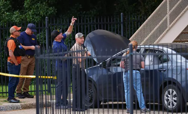 A law enforcement agents search a vehicle near the scene of a shooting at a U.S. Immigration and Customs Enforcement office in Dallas on Wednesday, Sept. 24, 2025. (AP Photo/Julio Cortez)