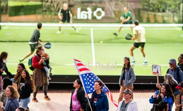 Protesters against immigration raids pass padel players in San Francisco on Thursday, Oct. 23, 2025. (AP Photo/Noah Berger)