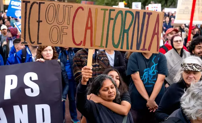 A mother and daughter, who declined to give their names, join protesters against immigration raids in San Francisco on Thursday, Oct. 23, 2025. (AP Photo/Noah Berger)