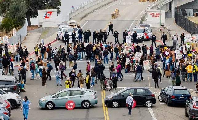 Protesters and vehicles block the entrance to Coast Guard Base Alameda shortly after a caravan of U.S. Customs and Border Protection personnel arrived on Thursday, Oct. 23, 2025, in Oakland, Calif. (AP Photo/Noah Berger)