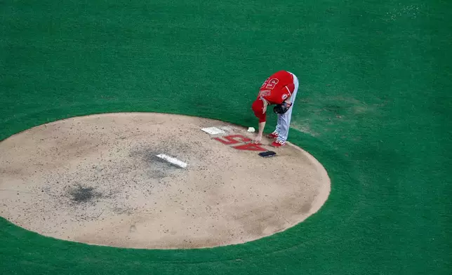 FILE - Los Angeles Angels relief pitcher Trevor Cahill reaches down to touch the number 45 on the back of the mound as he prepares to work against the Texas Rangers in the fifth inning of a baseball game in Arlington, Texas, July 2, 2019. (AP Photo/Tony Gutierrez, File)