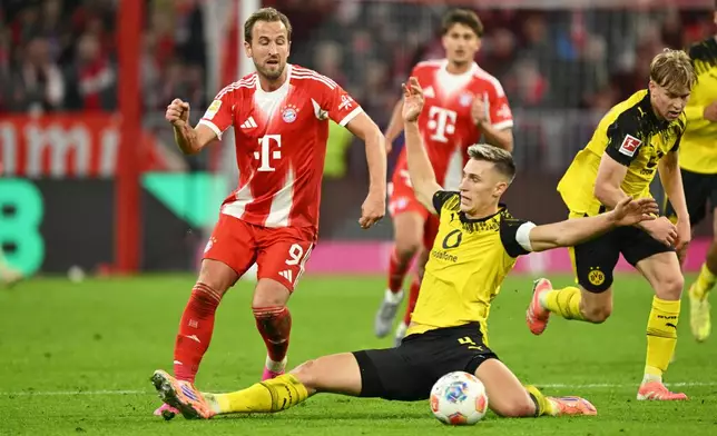 Bayern's Harry Kane, left, and Dortmund's Nico Schlotterbeck, centre, in action during the Bundesliga soccer match between Bayern Munich and Borussia Dortmund in Munich, Germany, Saturday, Oct. 18, 2025. (AP Photo/Lennart Preiss)