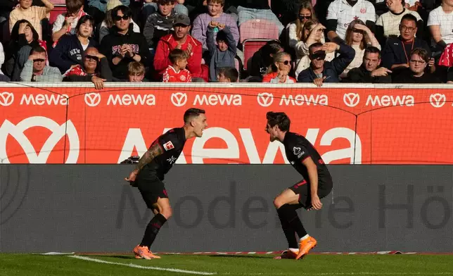 Leverkusen's Alex Grimaldo, left, celebrates with Leverkusen's Jonas Hofmann after scoring his side's third goal during the German Bundesliga soccer match between FSV Mainz 05 and Bayer 04 Leverkusen, in Mainz, Germany, Saturday, Oct. 18, 2025. (AP Photo/Michael Probst)