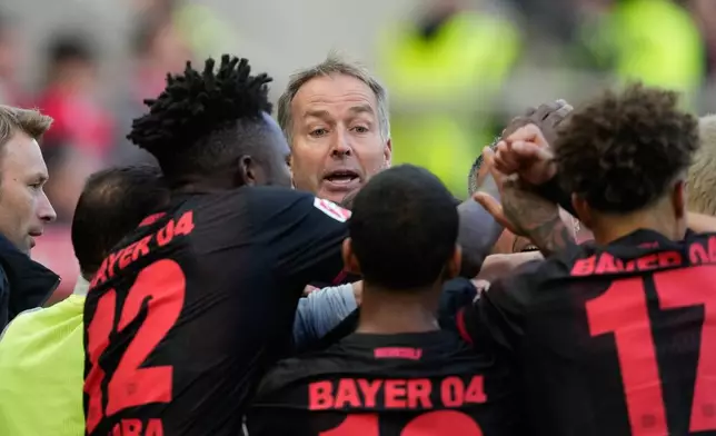 Leverkusen's head coach Kasper Hjulmand, center, celebrates with players after Leverkusen's Martim Terrier scoring fourth goal during the German Bundesliga soccer match between FSV Mainz 05 and Bayer 04 Leverkusen, in Mainz, Germany, Saturday, Oct. 18, 2025. (AP Photo/Michael Probst)