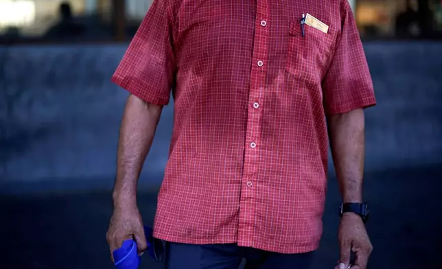 FILE - Pablo Suarez's shirt is bathed in sweat before seven in the morning as he parks cars and provides security for a downtown cafe July 20, 2023, in Mexicali, Mexico. (AP Photo/Gregory Bull, File)