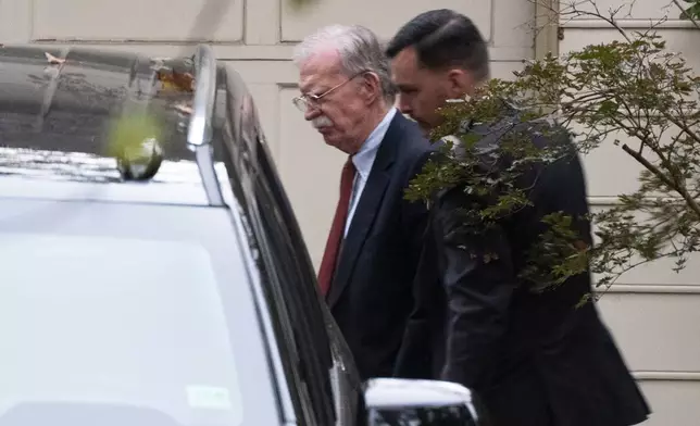John Bolton, left, who served as President Donald Trump's national security adviser during his first term, leaves his house in Bethesda Md., Friday, Oct. 17, 2025. (AP Photo/Manuel Balce Ceneta)