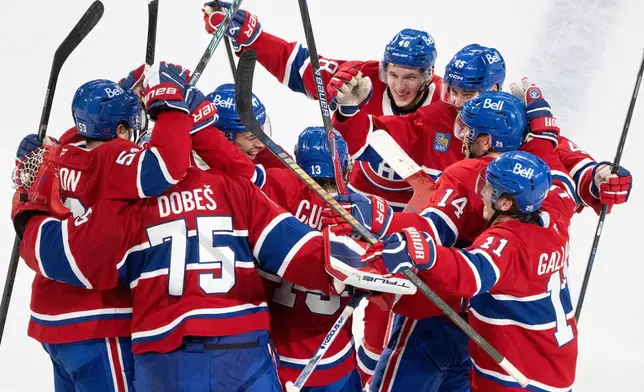 Montreal Canadiens' Cole Caufield (13) is surrounded by teammates after his winning goal over the Nashville Predators during overtime NHL hockey game action in Montreal, Thursday, Oct. 16, 2025. (Christinne Muschi/The Canadian Press via AP)