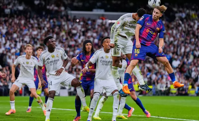 Barcelona's Fermin Lopez, top right, goes for a header with Real Madrid's Jude Bellingham during the Spanish La Liga soccer match between Real Madrid and Barcelona, in Madrid, Sunday, Oct. 26, 2025. (AP Photo/Manu Fernandez)