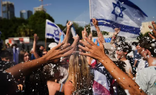 People wave Israeli flags and spray foam in celebration after the arrival of freed hostages at Beilinson Hospital in Petah Tikva, Israel, following their release from Hamas captivity in the Gaza Strip, Monday, Oct. 13, 2025. (AP Photo/Francisco Seco)