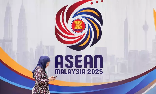 A woman walks in front logo of the Association of Southeast Asian Nations (ASEAN) ahead of the 47th ASEAN Summit in Kuala Lumpur, Malaysia, Friday, Oct. 24, 2025. (AP Photo/Vincent Thian)