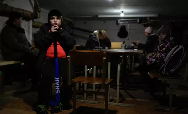 Tymofii Lifyrynko, 11, holds his hockey stick while waiting out an air raid alarm in an underground shelter, Thursday, Oct. 16, 2025, in Shostka, Ukraine. (AP Photo/Julia Demaree Nikhinson)