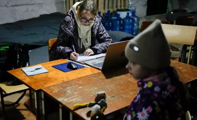 Sofia Sisa, 17, does homework in an underground shelter during an air raid alarm, Thursday, Oct. 16, 2025, in Shostka, Ukraine. (AP Photo/Julia Demaree Nikhinson)