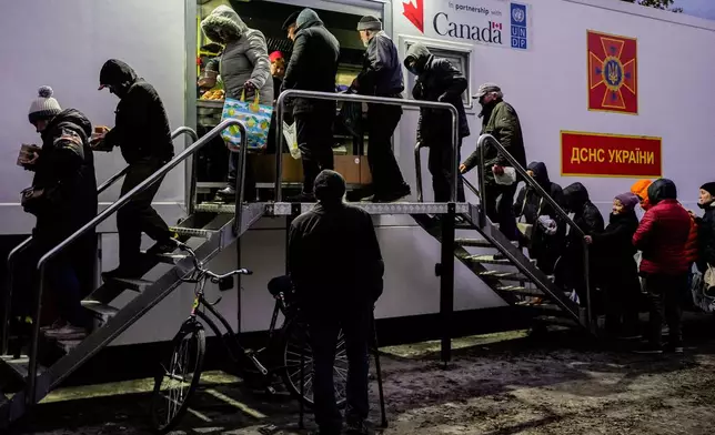 People receive free meals at a distribution point during a rolling blackout, Thursday, Oct. 16, 2025, in Shostka, Ukraine. (AP Photo/Julia Demaree Nikhinson)