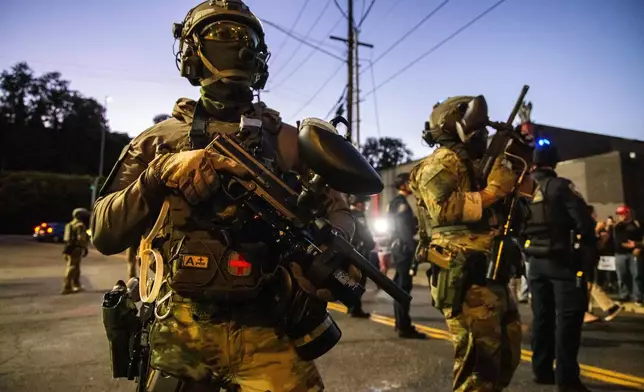 Federal enforcement officers stand guard near a U.S. Immigration and Customs Enforcement facility in Portland, Ore., Monday, Oct. 6, 2025. (AP Photo/Ethan Swope)