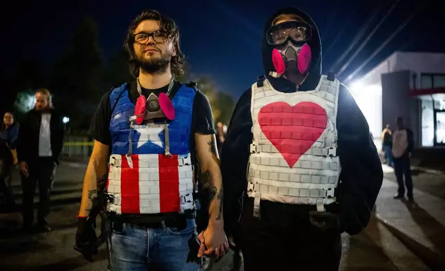 Demonstrators stand outside a U.S. Immigration and Customs Enforcement facility on Tuesday, Oct. 7, 2025, in Portland, Ore. (AP Photo/Ethan Swope)