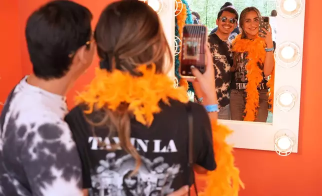 Roel Calderon, left, and Ashley Miramontes try on fashions inspired by Taylor Swift's new album, "The Life of a Showgirl," at a TikTok/Taylor Swift fan activation pop-up event to celebrate the release of the album on Friday, Oct. 3, 2025, in Los Angeles. (AP Photo/Chris Pizzello)