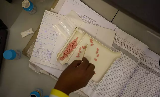 A pharmacist counts HIV medicine inside a clinic in Ha Lejone, Lesotho, July 16, 2025. (AP Photo/Bram Janssen)