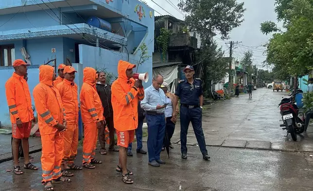 In this handout photo released by the National Disaster Response Force (NDRF), NDRF personnel warn residents of Cyclone Montha, in Yanam, in the Indian state of Andhra Pradesh, Monday, Oct. 27, 2025. (NDRF via AP)