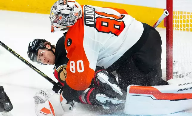 Ottawa Senators' Ridly Greig (71) slams into Philadelphia Flyers goaltender Dan Vladar (80) during third period NHL hockey action in Ottawa on Thursday, Oct. 23, 2025. (Sean Kilpatrick/The Canadian Press via AP)