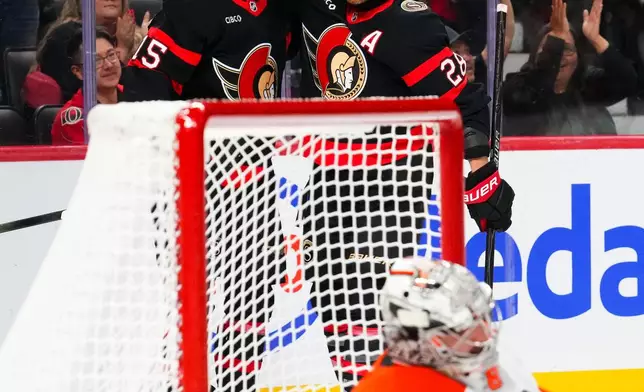 Ottawa Senators' Olle Lycksell (15) celebrates his goal with Claude Giroux (28) as Philadelphia Flyers goaltender Dan Vladar (80) sits on the ice during second period NHL hockey action in Ottawa on Thursday, Oct. 23, 2025. (Sean Kilpatrick/The Canadian Press via AP)