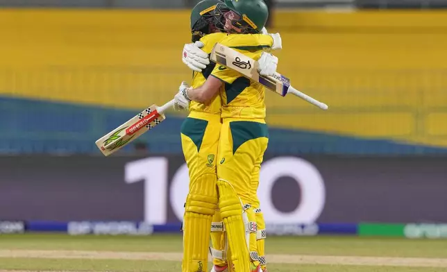 Australia's Beth Mooney, right, celebrates her century with Alana King during the ICC Women's Cricket World Cup match between Australia and Pakistan at Premadasa Stadium in Colombo, Sri Lanka, Wednesday, Oct, 8, 2025. (AP Photo/Eranga Jayawardena)