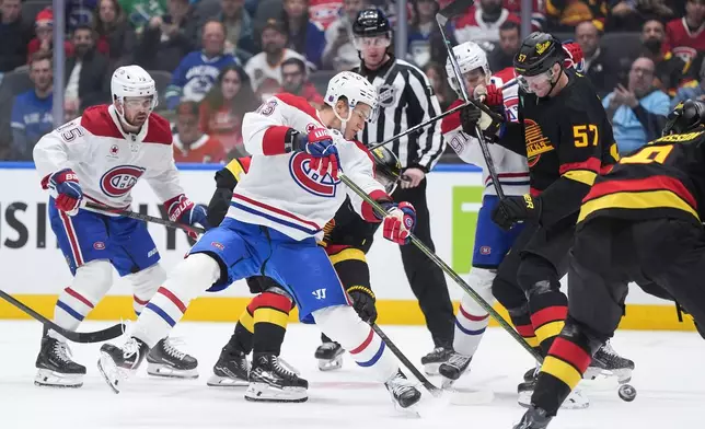 Montreal Canadiens' Ivan Demidov, center, shoots on goal as teammate Oliver Kapanen (91) checks Vancouver Canucks' Tyler Myers (57) during the first period of an NHL hockey game in Vancouver, British Columbia, Saturday, Oct. 25, 2025. (Darryl Dyck/The Canadian Press via AP)