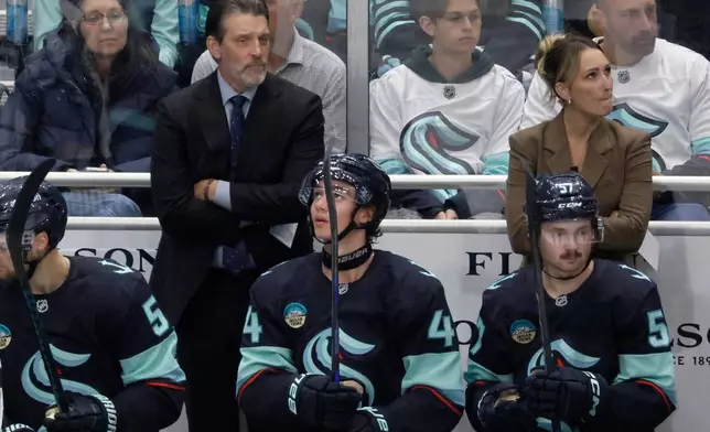 FILE - Seattle Kraken head coach Lane Lambert, left, and assistant coach Jessica Campbell, right, watch from the bench during the third period of a preseason NHL hockey game Sunday, Sept. 21, 2025, in Seattle. (AP Photo/John Froschauer, File)