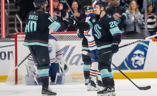 Seattle Kraken forward Eeli Tolvanen (20) celebrates with forward Matty Beniers (10) after scoring a goal during the first period of an NHL preseason hockey game against the Edmonton Oilers, Wednesday, Oct. 1, 2025, in Seattle. (AP Photo/Stephen Brashear)
