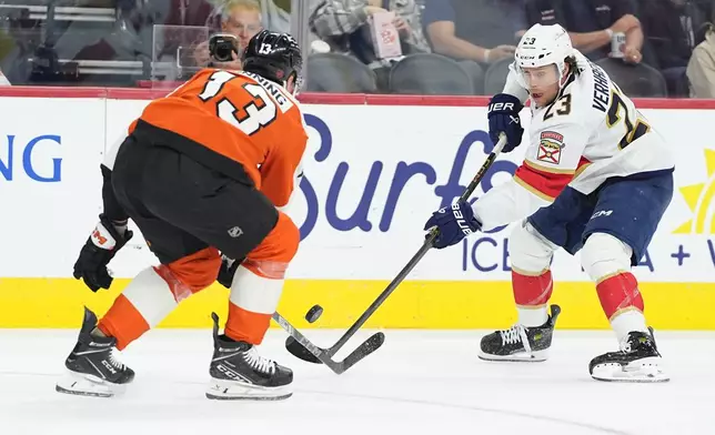 Florida Panthers' Carter Verhaeghe, right, passes the puck past Philadelphia Flyers' Adam Ginning, left, during the first period of an NHL hockey game, Monday, Oct. 13, 2025, in Philadelphia. (AP Photo/Matt Rourke)