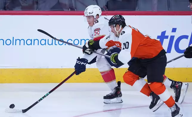 Florida Panthers center Anton Lundell, left, and Philadelphia Flyers right wing Bobby Brink, right, vie for the puck during the first period of an NHL hockey game, Monday, Oct. 13, 2025, in Philadelphia. (AP Photo/Matt Rourke)