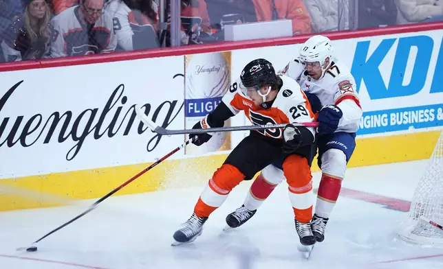 Philadelphia Flyers' Nikita Grebenkin, left, and Florida Panthers' Evan Rodrigues, right, battle for the puck during the first period of an NHL hockey game, Monday, Oct. 13, 2025, in Philadelphia. (AP Photo/Matt Rourke)