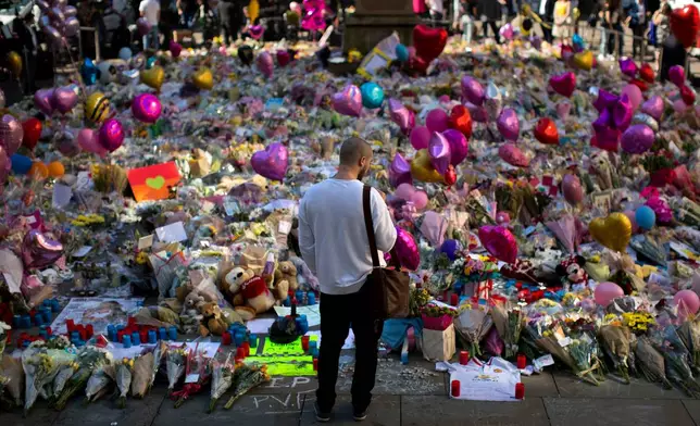 FILE - A man stands next to flowers for the victims of a bombing at St. Ann's Square in central Manchester, England, May 26, 2017. (AP Photo/Emilio Morenatti, File)